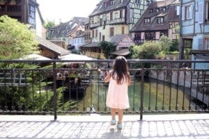 Back of little girl standing on bridge in Colmar France. France with kids.