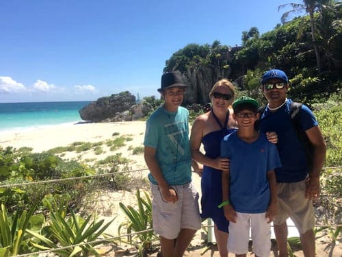 A family of four poses together on the beach near Tulum.