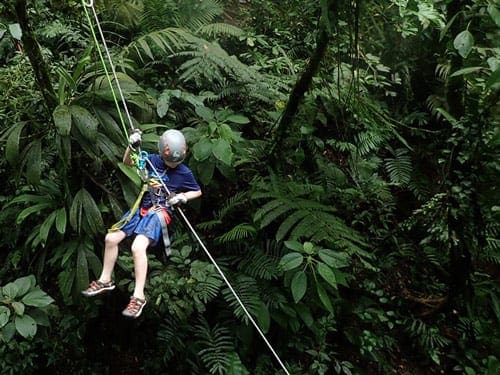 A young boy zip lining in La Fortuna, one of the best places to visit in Costa Rica with kids. 