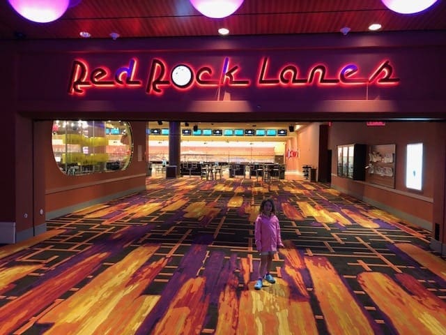 A girl stands in front of the entrance to Red Rock Casino Resort and Spa, featuring neon lights overhead.