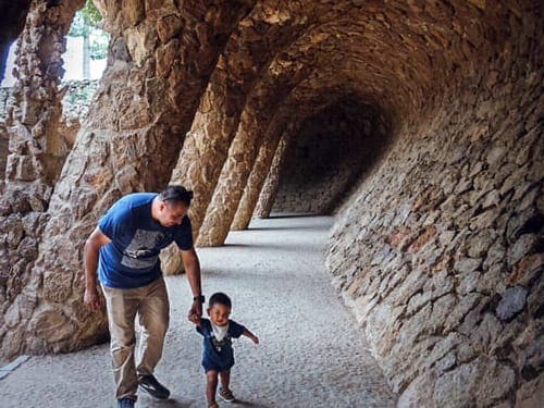 A dad and his young son explore a museum together with large stone walls.