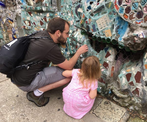 Father and daughter admiring colorful mosaic tiles in the Magic Garden of Philadelphia, one of the best US cities for a Memorial Day Weekend with kids.