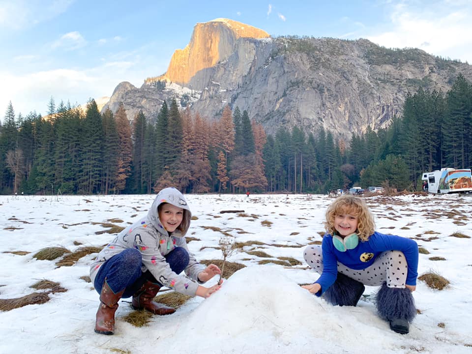 Two girls playing in snow at Yosemite National Park, one of the best national parks for families.