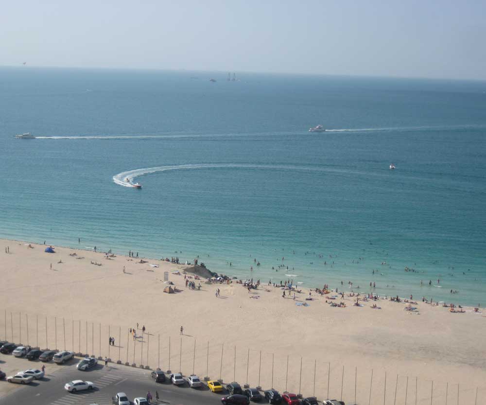 Boats in water and people on beach at Jumeirah Beach in Dubai