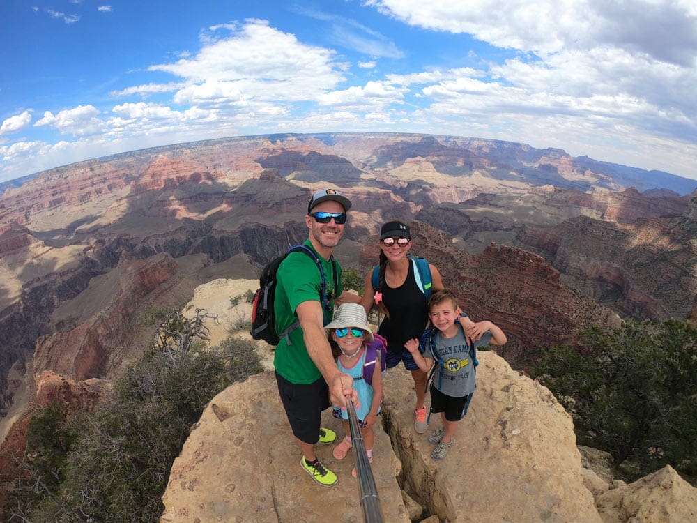 Family taking selfie in Grand Canyon, one of the best affordable summer vacations in the United States with kids.