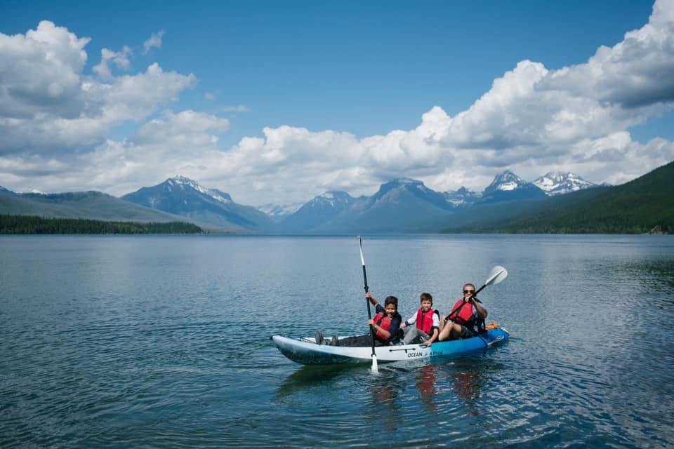 Family of three in a kayak on the lake in Glacier National Park.