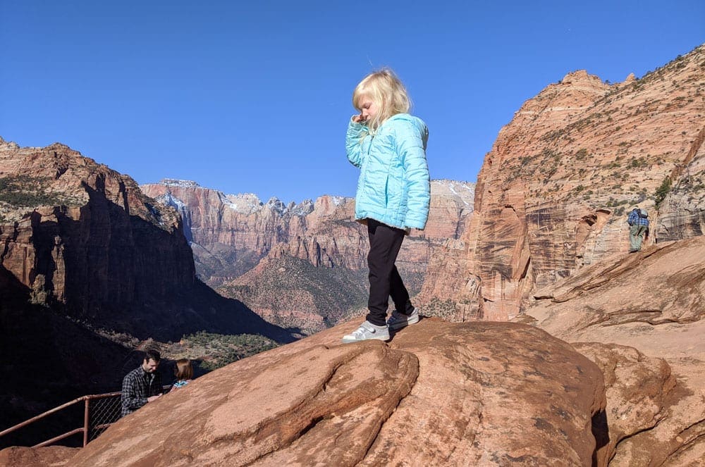 A young girl walks across a large rock in Zion National Park.