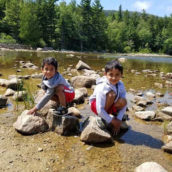 Two boys on rocks in lake at Acadia.