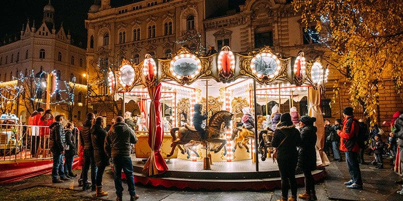 Several people stand around the lit Christmas carousel at the Zagreb Christmas Market.