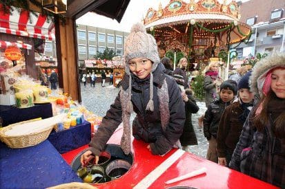 A young boy leans over a Christmas market stall.
