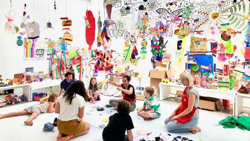 Several kids and staff members do an activity in a very vibrant and colorful room at The GIANT Room.
