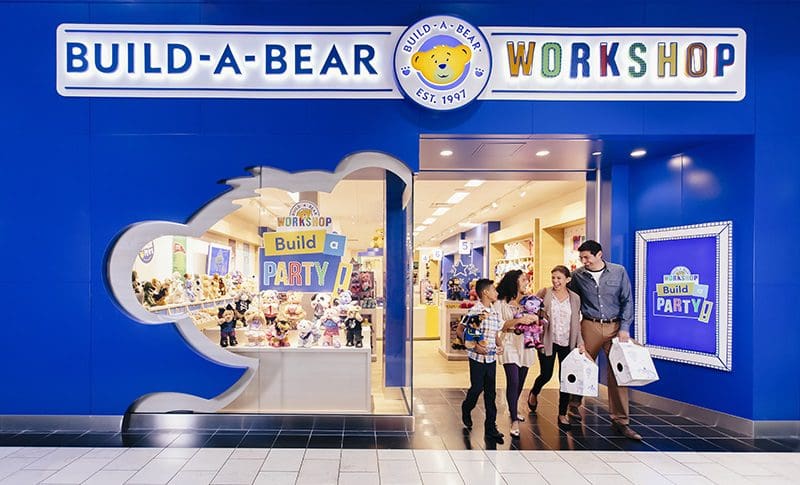 A happy family leaves Build-A-Bear Workshop with their new teddy bears.