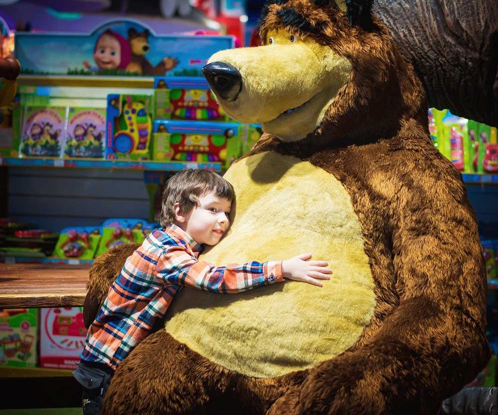 Boy hugging giant plush bear at New York City toy store