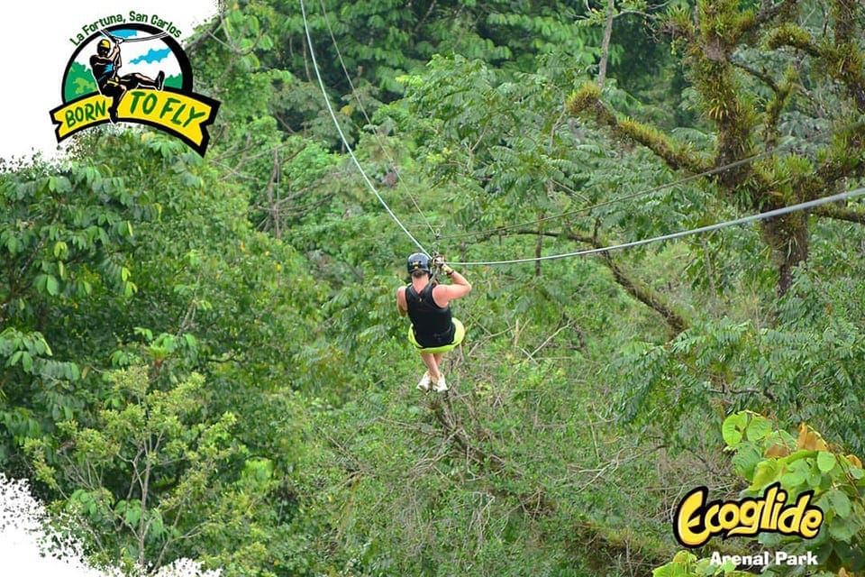 A man zip-lines across a line at the Arenal Ecoglide Park, which is one o the best things to do in Costa Rica with kids.