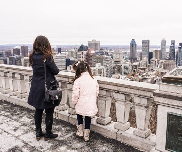 A woman and her daughter look out at the Montreal skyline.