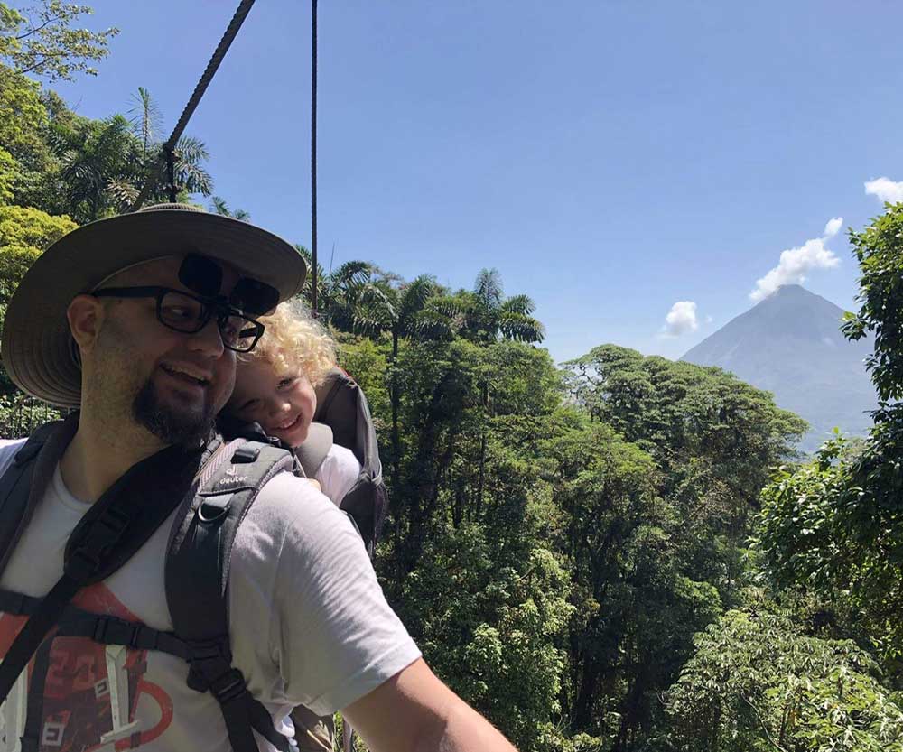 A father and his toddler overlooking the Arenal Volcano on a hike in Costa Rica.