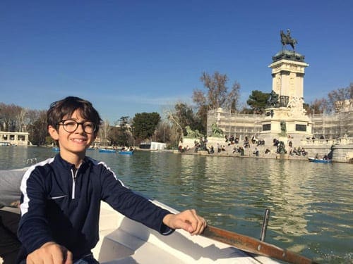 Boy with glasses rowing boat in water in Madrid.