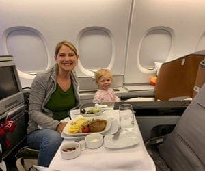 A mom and her child on a Lufthansa flight. They're enjoying a meal, which is a point in our list of Lufthansa Airline Policies For Kids and Infants.