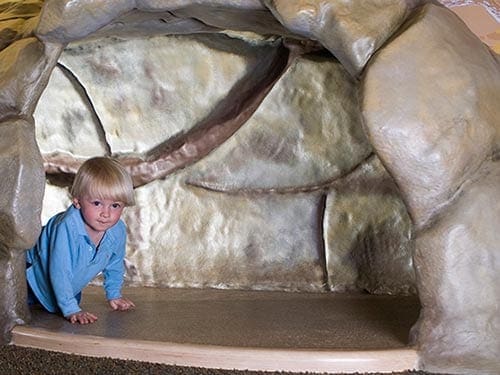 A young child crawls through a tunnel, while playing at Treehouse Kids’ Adventure Center.
