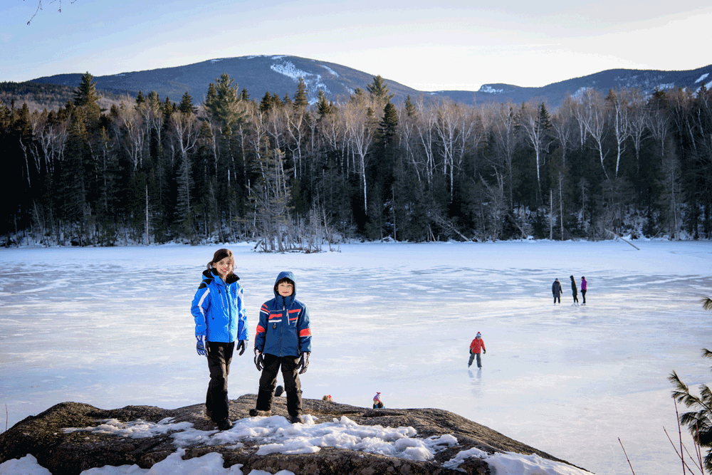 Brother and sister posing on the frozen Flagstaff Lake while skiing in Maine for families.