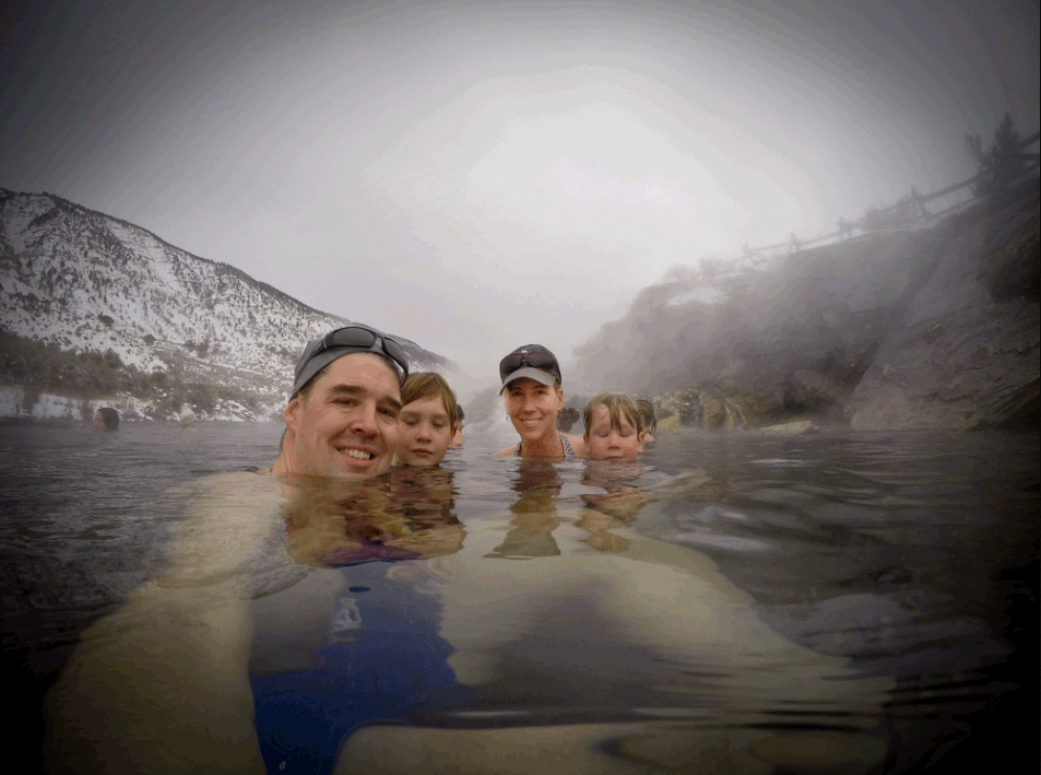 A family of four enjoying the Yellowstone National Park hot spring on a cold day.