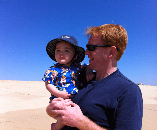Father and baby with sun hat on the beach