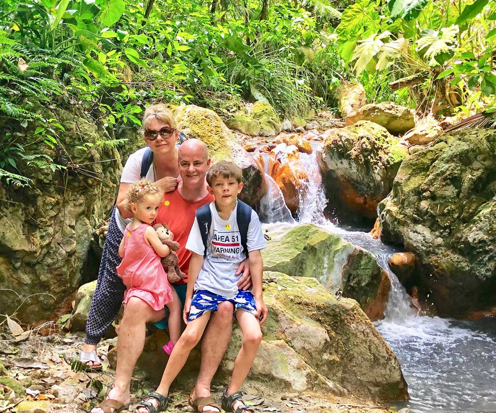 Family hiking near a waterfall in St. Lucia, one of the best affordable Caribbean islands for families 