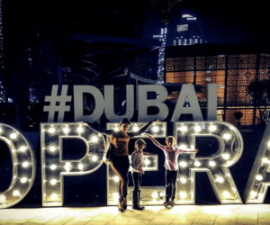 Mother with two girls standing in front of Dubai Opera lighted sign