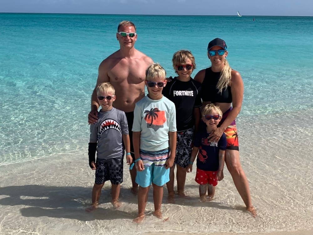 A family of five, including four children, stands together posing in the water off-shore from Turks and Caicos.