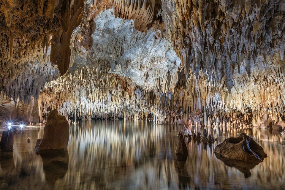 Inside the Cayman Crystal Caves, one of the best things to do in Grand Cayman with kids, featuring large rock formations and crystal clear water.