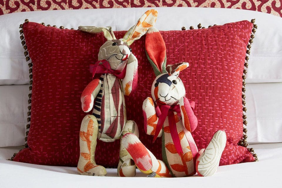 Two vibrant rabbit stuffed animals rest against a hotel pillow at Covent Garden Hotel.