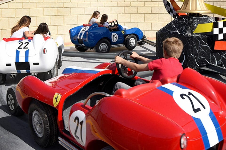 Several kids drive ride cars at Ferrari Land.