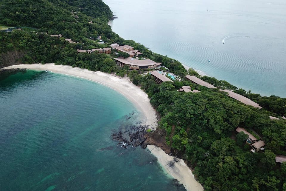 An aerial view of Four Seasons Resort Costa Rica at Peninsula Papagayo, one of the best Costa Rica resorts for a family vacation, nestled along a sandy Costa Rican shore.