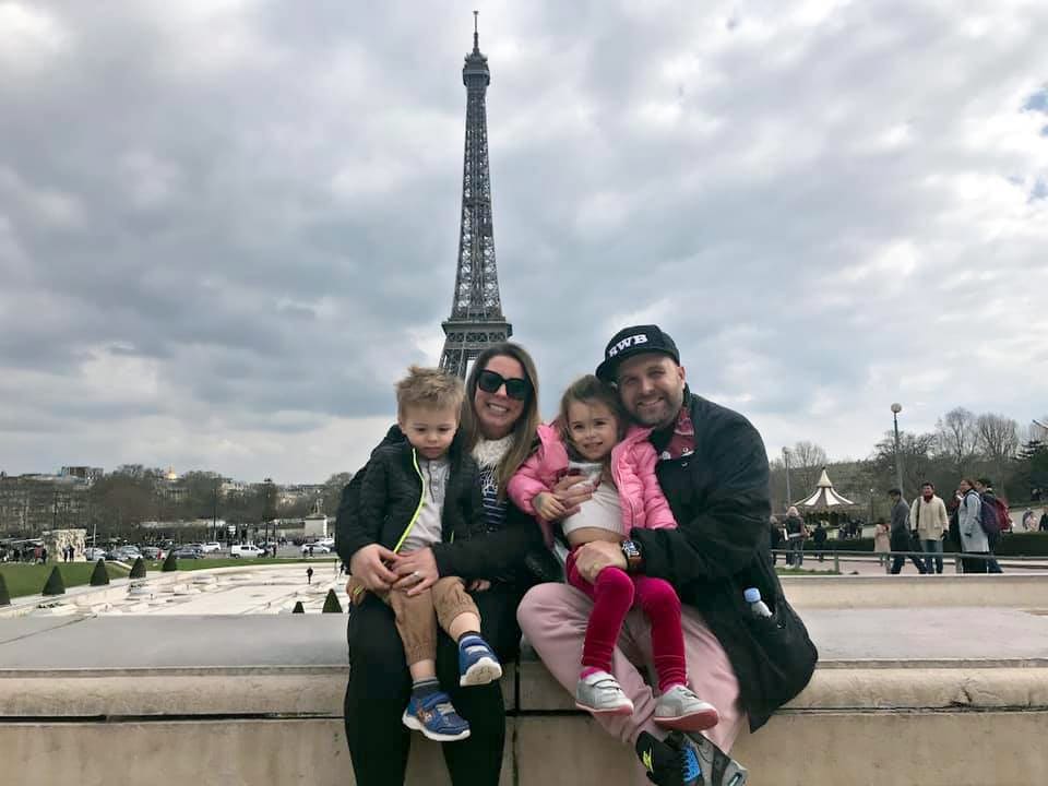 Family of four sits in front of the Eiffel Tower, one of the stops on our virtual vacation from home to Paris.