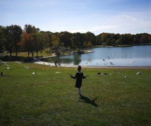 A young girl runs through a field alongside a lake in Montreal on a crisp, fall day.