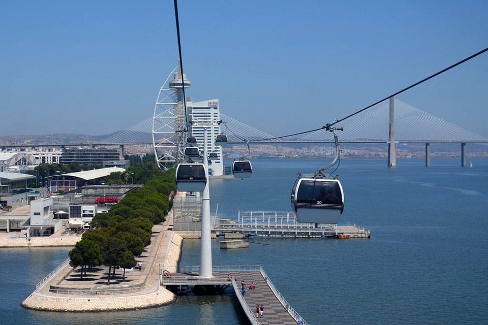 A view of several cars on the Lisbon Cable Car over the water.