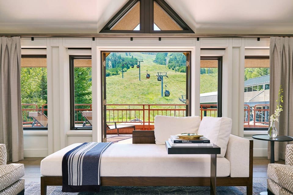 Inside a lush suite at The Little Nell with a view of the mountain and ski lift out the window during the summer at one of the best eco-friendly hotels in the United States for families.