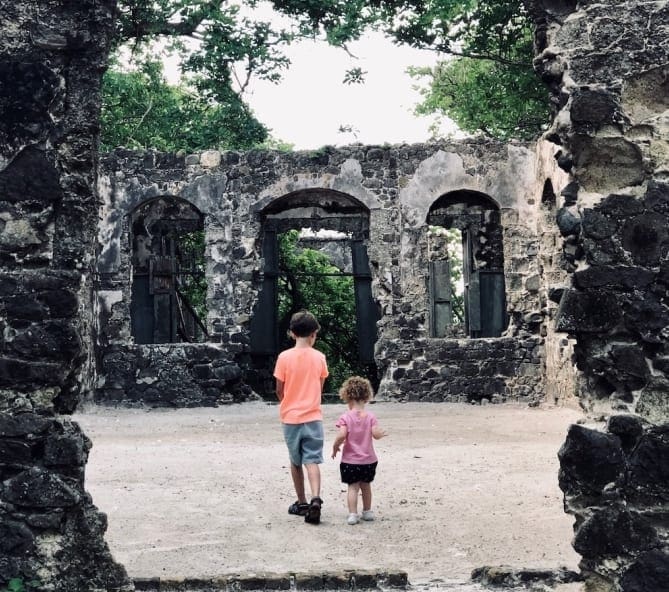 Two kids walk into a historic arch while exploring as a family.