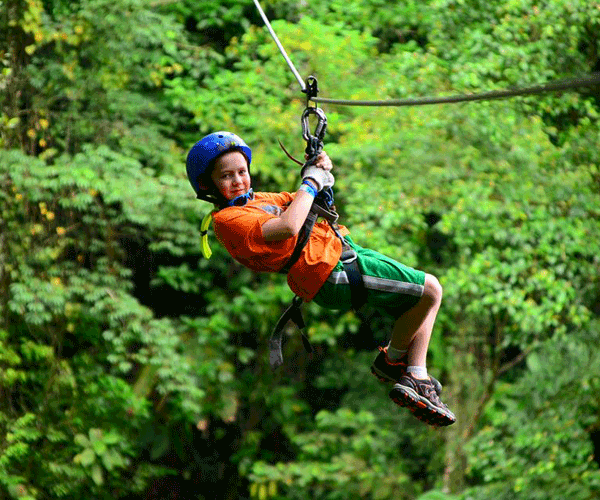 A young boy flies through the Costa Rican canopy on a zip-line.