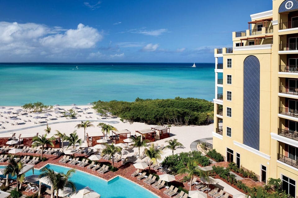 Aerial view of The Ritz-Carlton, Aruba, one of the best family resorts in Aruba, showcasing a pool, expansive beach, and large buildings.