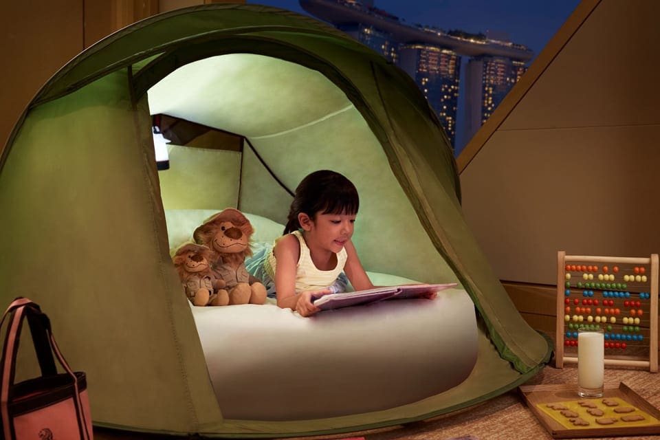 A young girl sleeps in a play tent with her teddy, while staying at The Ritz-Carlton, Millenia Singapore.