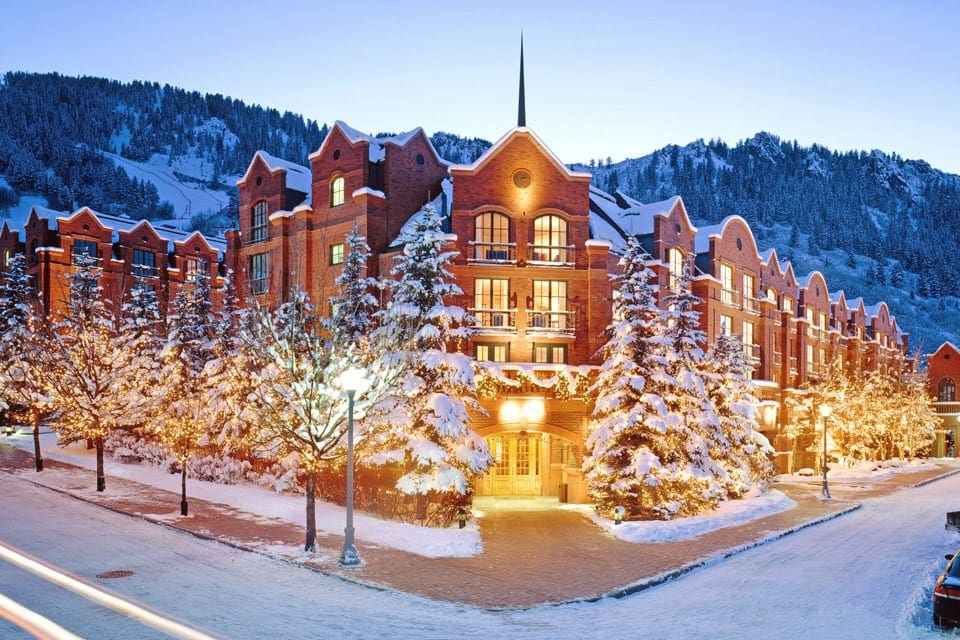 The corner entrance to St. Regis Aspen Resort on a snowy night, the hotel seems to glow in the winter night.