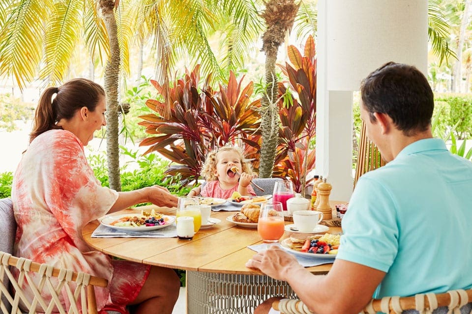 Two people and their young daughter eat a delicious meal for breakfast at The Jumby Bay Island Resort.