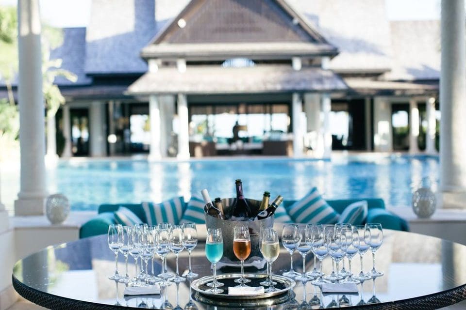 A series of drinks are placed on a table in front of a pool at Jumby Bay Island Resort, one of the best family resorts in Antigua.