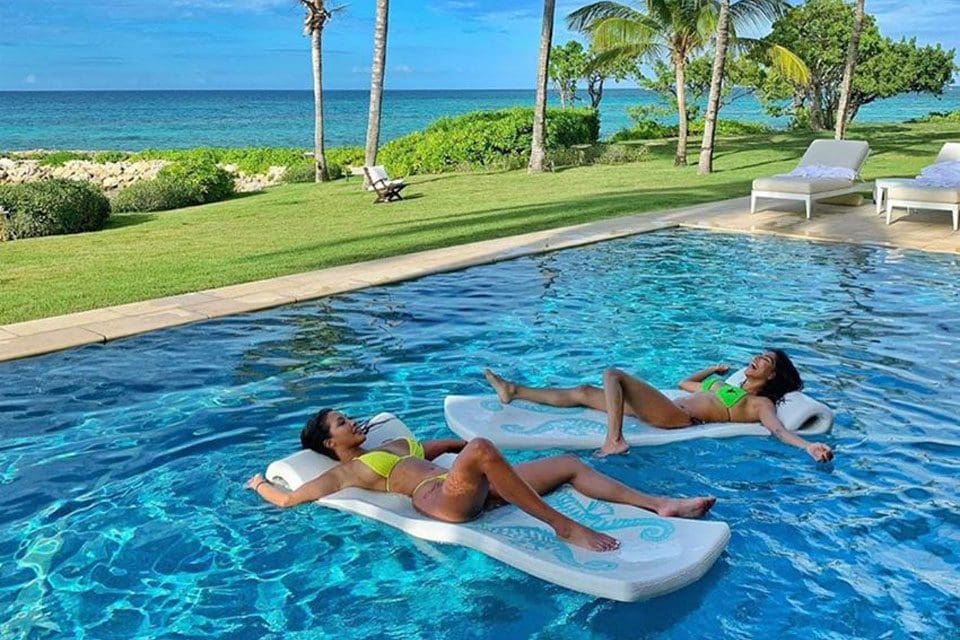 Two people, floating on pool flotation devices, relax in the pool at The Jumby Bay Island Resort.