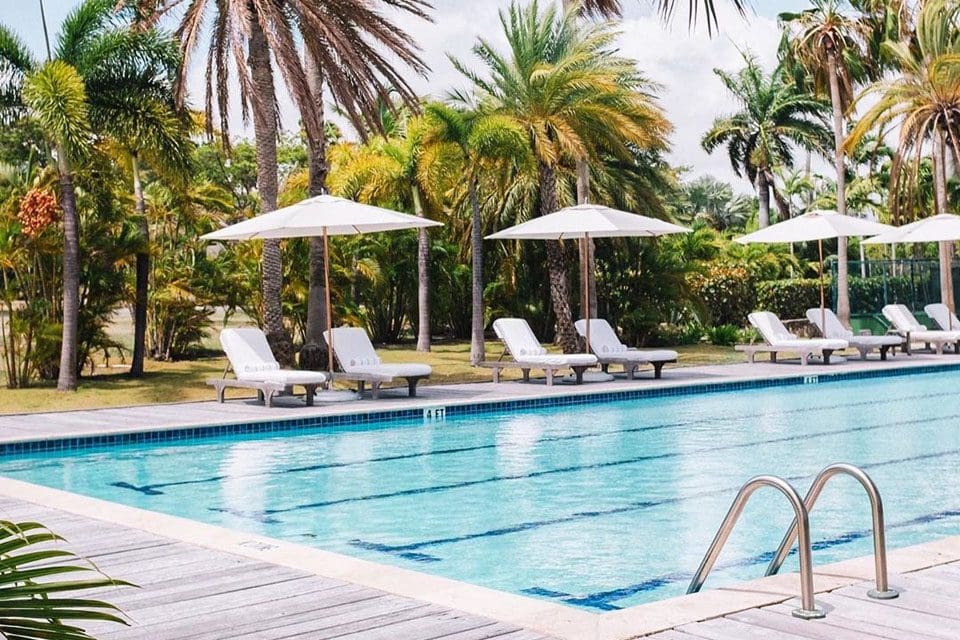 The tranquil pool, with a line of poolside loungers and umbrellas, at The Jumby Bay Island Resort.