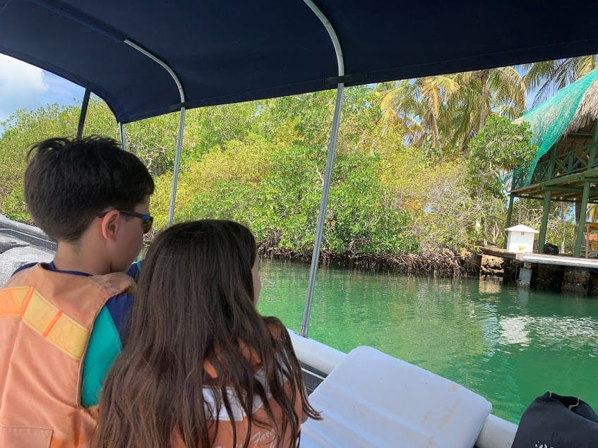 Two kids enjoying a boat tour in Cartagena look out onto the turquoise water, one of the best things to do on this Cartagena itinerary for families.