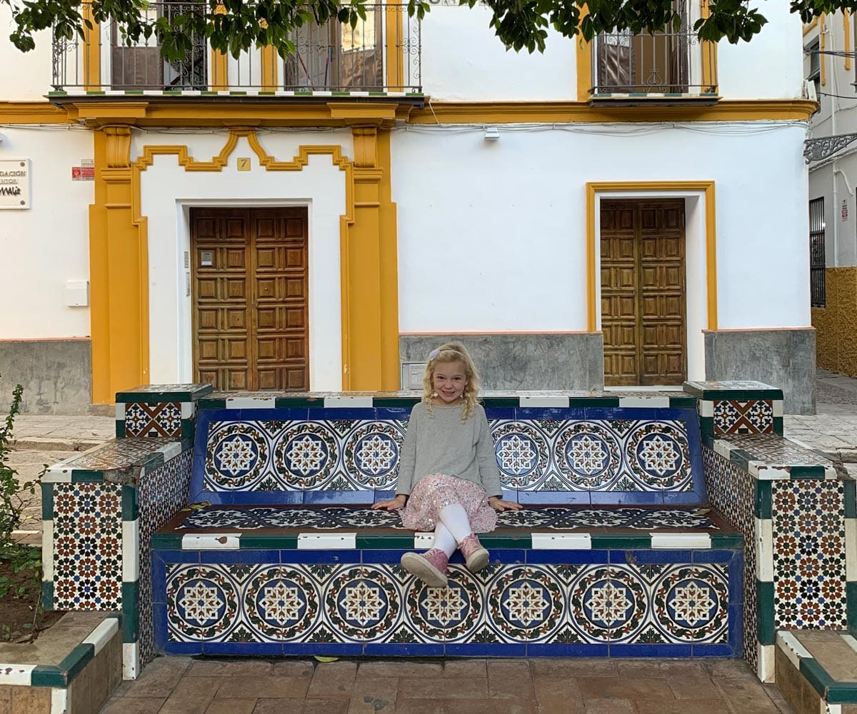 A young girl sits on colorful steps in Seville.