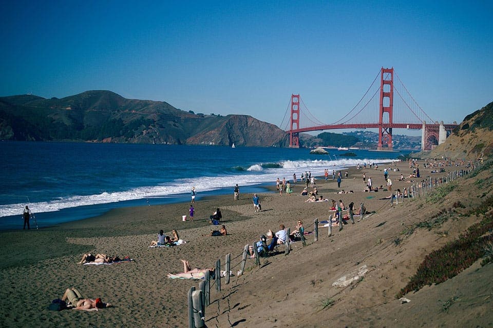 Baker Beach with Golden Gate Bridge in background, and beach-goers on the sand.