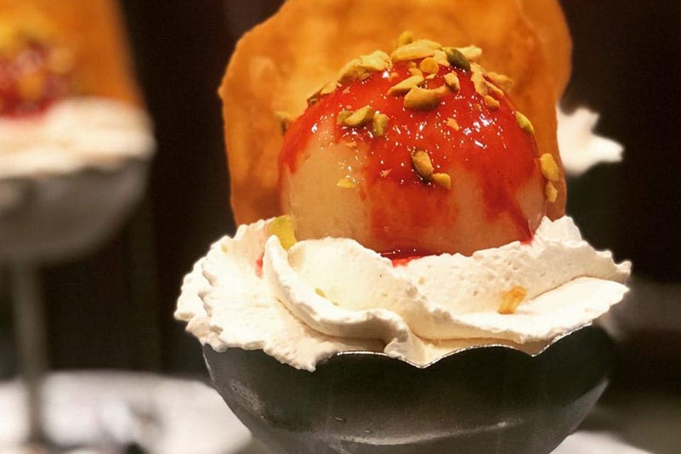 A close up of a Parisian dessert, featuring whipped cream and a red sauce, at Berthillon, one of the best dessert destinations in Paris for families.